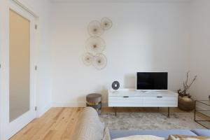 a living room with a couch and a tv on a wall at GuestReady - Cosy and Modern Apartment 4mins from Metro in Porto