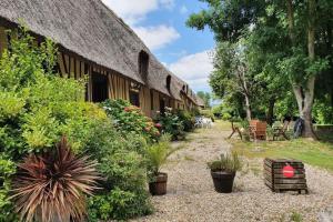 a building with a thatched roof with plants in front at La Chaumière de Mano in Berville-sur-Mer