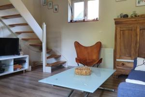 a living room with a table and a staircase at La Chaumière de Mano in Berville-sur-Mer