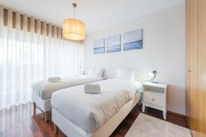 a white bedroom with two beds and a window at GuestReady - Go To Sleep in Porto