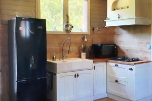 a kitchen with a black refrigerator and a sink at La Chaumière de Mano in Berville-sur-Mer