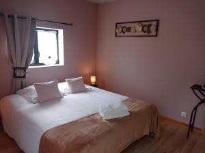 a bedroom with a bed with white sheets and a window at La villa Saint-Martin in Pontorson