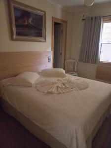 a bedroom with a white bed with a dress on it at Pousada Eco Da Montanha in Passa Quatro
