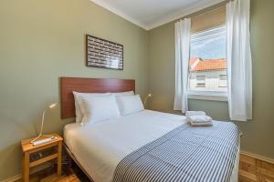 a bedroom with a large bed with a window at GuestReady - City & Beach Garden Home in Porto