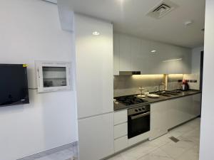 een keuken met witte kasten en een fornuis met oven bij Furnished studio استديو مفروش studio city in Dubai