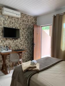 - une chambre avec un lit, un bureau et une télévision dans l'établissement Suíte 101- Espaço Praia Aptos, à Angra dos Reis