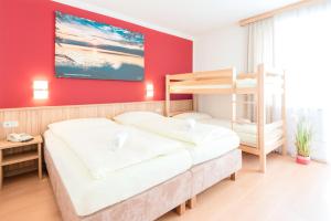 1 Schlafzimmer mit 2 Etagenbetten und einer roten Wand in der Unterkunft Gasthof Menüwirt in Sankt Kanzian am Klopeiner See