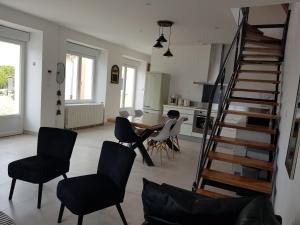 sala de estar con escalera, mesa y sillas en Mon Gîte en Château-du-Loir