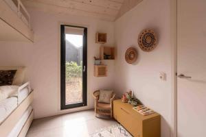 a bedroom with a bed and a table and a window at WØUD Tiny House in Epe