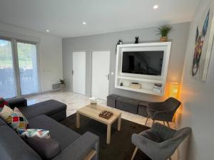 ein Wohnzimmer mit einem Sofa und einem TV in der Unterkunft Belle maison avec jacuzzi in Bretteville-sur-Odon