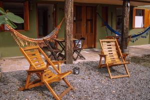 2 Stühle und eine Hängematte vor einem Haus in der Unterkunft Quinta dos Samaniego - Chalés Rústicos in Itaúnas