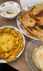 4 platos de comida en una mesa de madera en Swiss Cottage Bhurban, en Bhurban