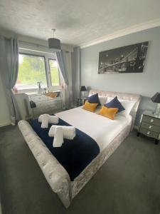 a bedroom with a large bed with yellow and blue pillows at The Brook House - Spacious 3 Bed Home From Home in Burton upon Trent