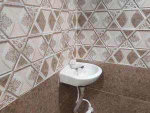 a white sink in a bathroom with tiled walls at Hotel Nova Atlanta Shopping Mall in Surat