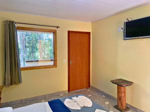 Habitación con cama, ventana y TV. en Pousada Casinha Velha, en Macacos