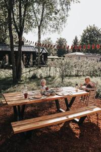 Dos personas sentadas en una mesa de picnic con comida. en Hjort I Tiny House, en Epe