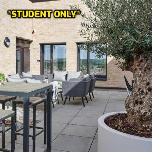 an outdoor patio with tables and chairs and a tree at Student Only Zeni Ensuite Rooms, Southampton in Southampton