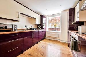 una cucina con armadi in legno e una grande finestra di GuestReady - Classy haven near Camden Town a Londra