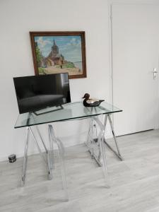 un escritorio de cristal con una silla y una foto en Les Mulotières en Olivet