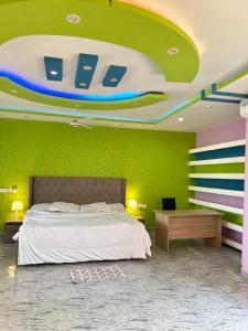 Regitton Hotel في Denu: غرفة نوم بسرير وجدار أخضر
