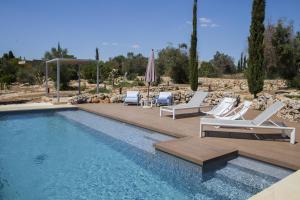 einen Pool mit weißen Liegestühlen und einem Sonnenschirm in der Unterkunft Villa Platino in Torre Vado