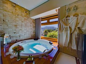 a bathroom with a large tub and a window at Hotel Harmonia Monte Verde in Monte Verde