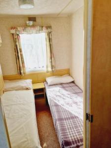 2 camas en una habitación pequeña con ventana en Golden Sands Park Ingoldmells, en Ingoldmells