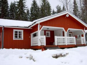 uma casa vermelha com neve em frente em Holiday home TORSBY VII em Torsby