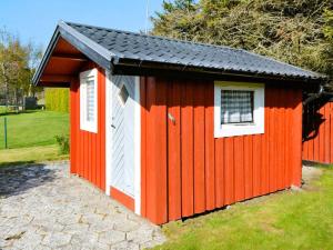 einem roten und weißen Schuppen mit schwarzem Dach in der Unterkunft Holiday home LAHOLM XV in Laholm