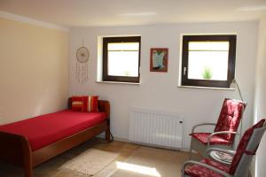 a bedroom with a red bed and two windows at Gästehaus Silbersbach in Seibersbach