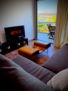 uma sala de estar com uma televisão, um sofá e uma mesa em Seashore Happiness Apartments em Porto Rafti