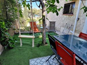 un patio trasero con hamaca, mesa y sillas en Studio Au bas des crêtes en bas de villa à La Ciotat proche de la mer et de Marseille, en La Ciotat