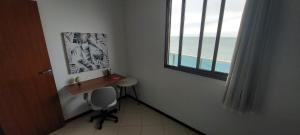 a room with a desk and a chair and a window at Quarto in Vila Velha