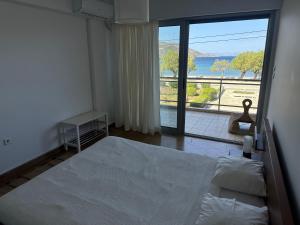 um quarto com uma cama e uma grande janela em Seashore Happiness Apartments em Porto Rafti