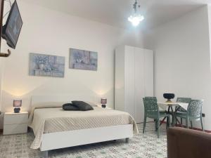 een slaapkamer met een bed en een tafel en stoelen bij Cairoli Apartments in Licata