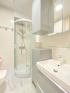 een witte badkamer met een douche en een wastafel bij Cosy and lovely flat close to Eiffel Tower in Parijs