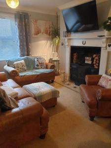 a living room with couches and a fire place at Cosy 3-Bed House in Kidwelly in Kidwelly
