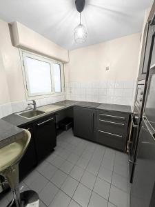 uma cozinha com armários pretos, um lavatório e uma janela em Chic Parisien en Cœur de Ville em Paris