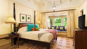 Schlafzimmer mit einem Bett, einem TV und einem Fenster in der Unterkunft The Oberoi Udaivilas Udaipur in Udaipur