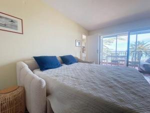 a bedroom with a large bed with blue pillows at Vue baie à 5min de la plage 44m² avec parking in Théoule-sur-Mer