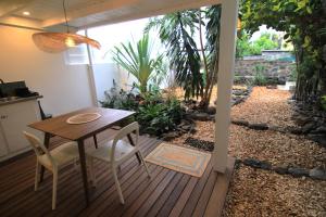 a wooden table and chairs on a deck with a garden at Studio Kaza Blanka - Saint Leu - Réunion in Saint-Leu