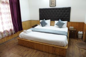 a bedroom with a large bed with a black headboard at Ramta Jogi Hotel & Stays in Manāli