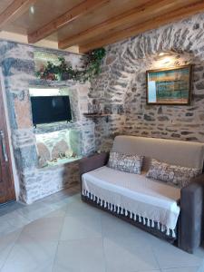 a room with a stone wall with a couch and a tv at ΜΕΣΤΑ - ΠΛΑΤΕΙΑ in Mestá