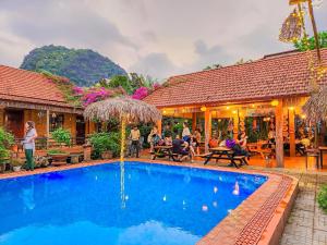 a resort with a swimming pool in front of a building at Trang An Village Homestay in Ninh Binh