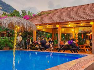 grupa ludzi siedzących wokół basenu w obiekcie Trang An Village Homestay w mieście Ninh Binh
