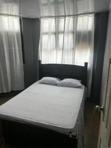 een bed met witte lakens en kussens voor een raam bij Hotel Rio Puntarenas in Puntarenas