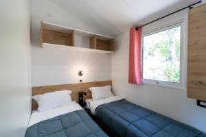 - 2 lits dans une petite chambre avec fenêtre dans l'établissement Camping Le Damier, à Pianottoli-Caldarello