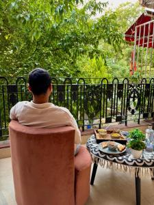 Atharva's Homestay by Goaround Homes في نيودلهي: رجل يجلس على كرسي بجانب طاولة