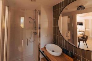 a bathroom with a shower with a sink and a mirror at Lille lykke I Tiny House op de Veluwe in Epe