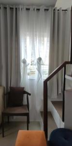 a room with a chair and a window with curtains at Cosy House in Bacolod City in Bacolod